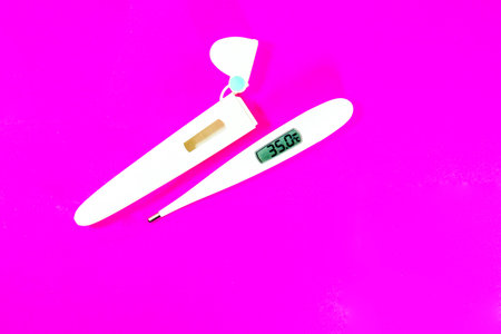 Terumo digital clinical thermometer  for check a feverÂ fight coronavirus on pink background.