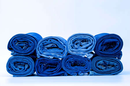 Roll Frayed jeans or blue jeans denim collection on white table background with copy space, fashion style concept.の写真素材