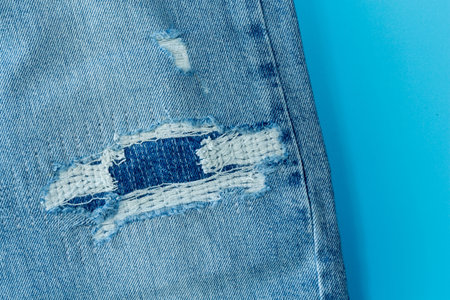 Hole on Denim Jeans. Ripped Destroyed Torn Blue jeans background. Close up blue denim jean texture