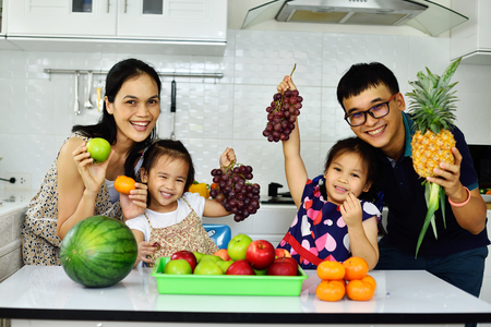 Happy Asian family show fruit in hand, eating healthy conceptの写真素材