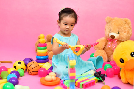 Cute Asian girl playing toys in pink living roomの写真素材
