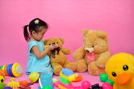 Cute Asian girl playing teddy bear in living roomの写真素材