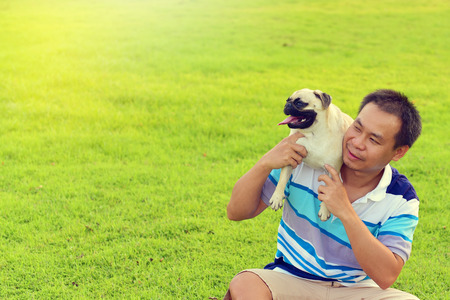 Happy Asian man playing with his dog in gardenの写真素材