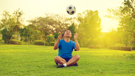 Asian man playing football alone in gardenの写真素材