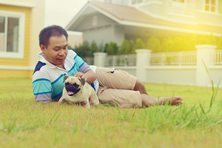 Happy Asian man playing with his dog in gardenの写真素材
