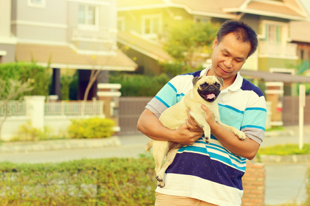 Happy Asian man playing with his dog in gardenの写真素材