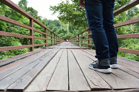 A man on a wooden bridge in the jungle, a long way ahead.の写真素材