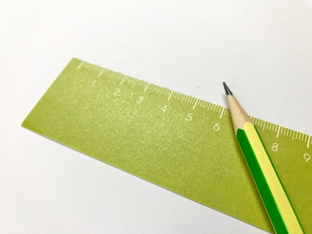 Green ruler and pencil on white background.の素材