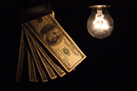 Hanging light bulb dangle on a wire illuminating bank notes