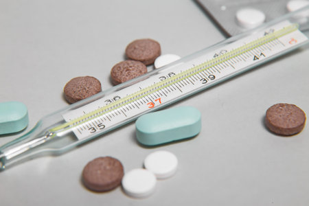 Bunch of blue pills with thermometer on the white backgroundの写真素材