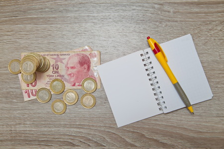 A blank notebook page and pen and Turkish Lira on wood office table. Top view with copy space.の写真素材