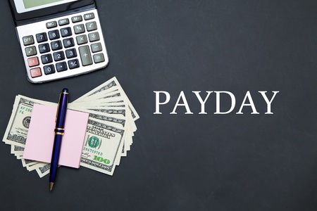 US Dollars on black office table with message PAYDAYの写真素材