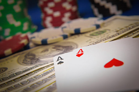 Close up of playing cards, poker chips and money.