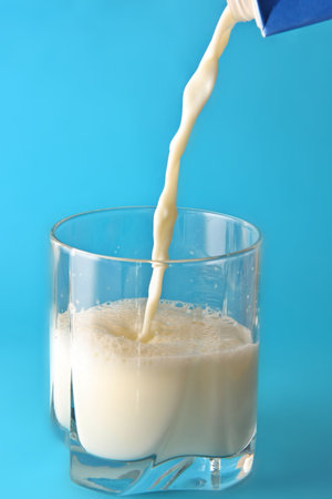 Milk poured in glass with blue backgroundの写真素材