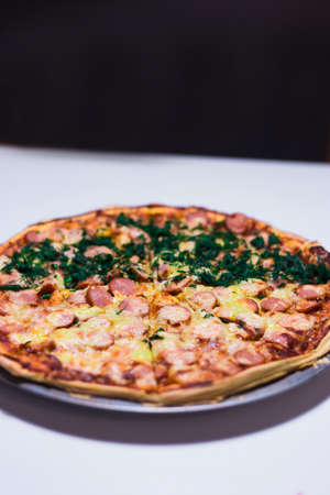 Home-made pizza whith sausages, cheese and dill on white tableの写真素材