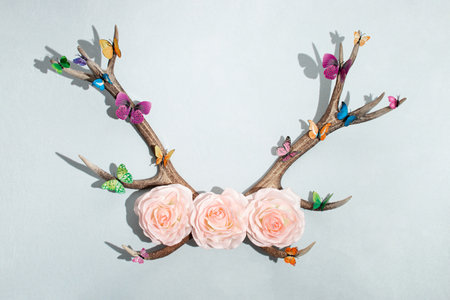 Spring concept made of deer antlers, flowers and butterflies and shadows, on pastel light blue background. Minimal spring idea. Flat lay top view composition.の写真素材
