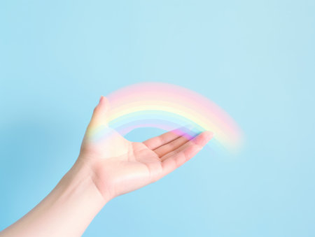 A person holding a rainbow in their hand against blue background.の素材