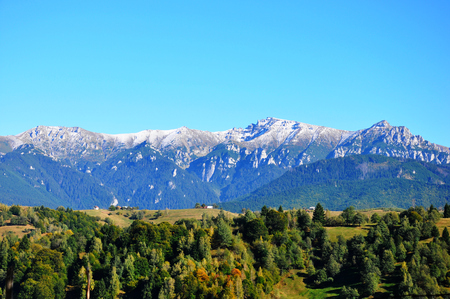 Beautiful three colore landscape representing forested hills, snowy mountains and blue skyの写真素材