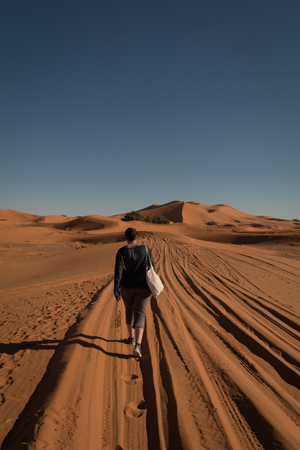 Solo female traveler hiking in the distance in the Sahara desertの写真素材