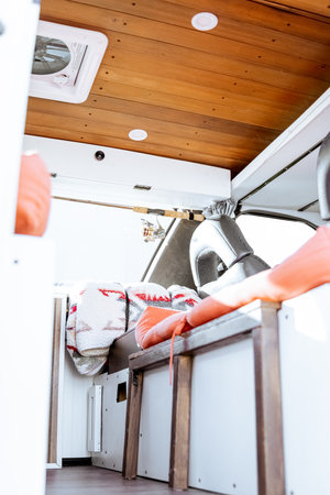 Beautiful bright natural light entering and illuminating an old self converted minivan campervan for van life. The vanlife recreational vehicle has orange seat cushions, stained roof, and van plant.の写真素材
