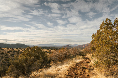 Hiking trail at the popular Airport Mesa loop hike in Sedona Arizona USA southwest during the day with beautiful clouds in the sky looking west.の写真素材