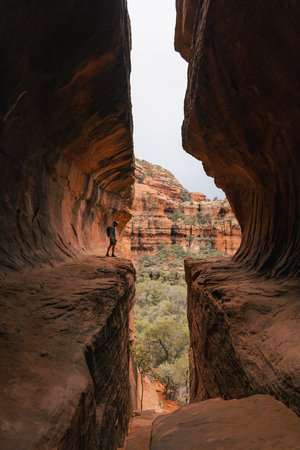Young man hiker stands in Subway Cave in Boynton Canyon Sedona Arizonaの写真素材
