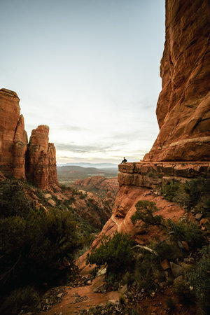 Wide angle view of woman sitting at sunset in Sedona Arizona from Cathedral Rock Viewpoint.の写真素材
