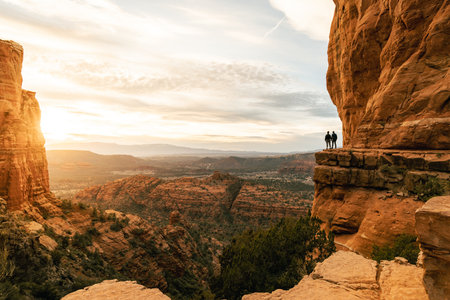 Young heterosexual couple holds hands at viewpoint during dramatic sunset from Cathedral Rock in Sedona.の写真素材