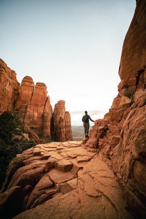 Vertical wide angle view of woman standing at sunset from Cathedral Rock in Sedona.の写真素材