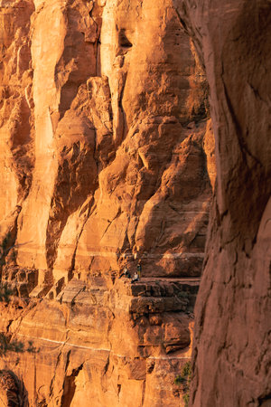 People enjoy grand view at Cathedral Rock Summit at sunset with golden hues.