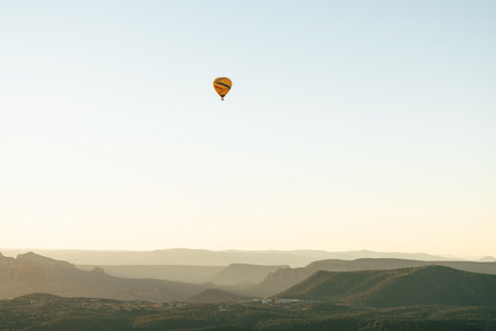 Horizontal image of wide shot of hot air balloon isolated against white sky background in early morning flight.の写真素材