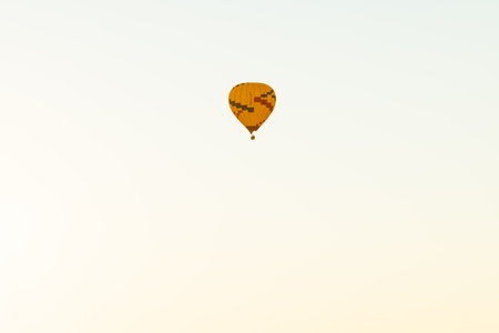 Super telephoto image of hot air balloon isolated against white sky background in early morning flight.の写真素材