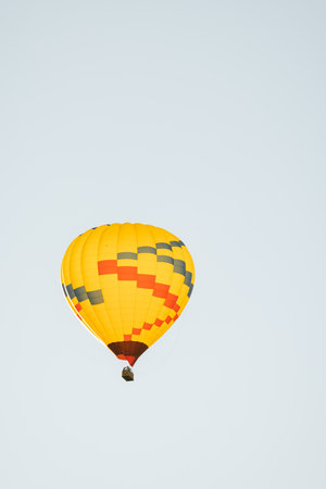 Low angle view of yellow hot air balloon in Sedona Arizona isolated against light blue sky background in early morning.の写真素材