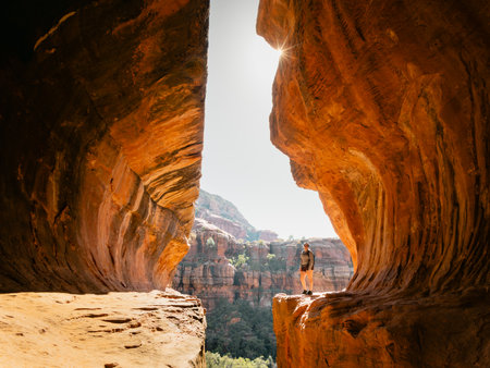 Low angle view Secret Subway Cave Boynton Canyon Sedona with a solo female hiker posing near cliff.の写真素材