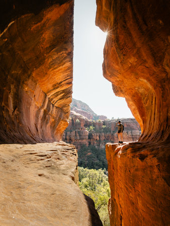 Secret Subway Cave Boynton Canyon Sedona solo female hiker standing next to cliff with sunstar.の写真素材
