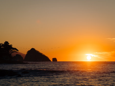 Sun setting near Parque Nacional Marino Los Arcos de Mismaloya in Puerto Vallarta Mexico over ocean.の写真素材