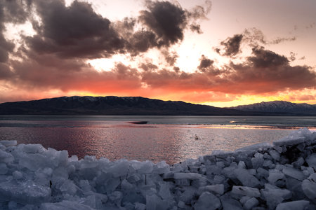 Ice stacks in foreground and bright orange sunset over Utah Lake.の写真素材