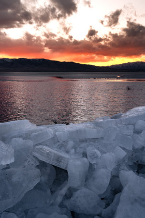 Ice stacks in foreground and bright orange sunset over Utah Lake.の写真素材