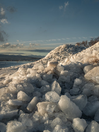 Ice stacks in vertical image at Vineyard Beach on Utah Lake in Utah at sunset in February 2025.の写真素材