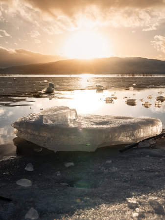 Vertical image Ice stacks in foreground at Vineyard Beach on Utah Lake in Utah at sunset in February 2025.の写真素材
