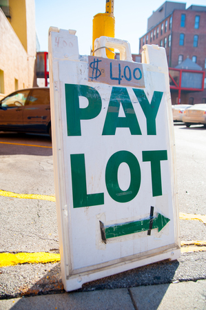 Sign $4 PAY LOT at the country side in America. America is a continent where American mainly live.