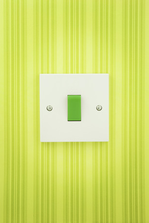 Green Switch on a white socket with a stripy wall paper background