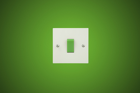 Green Switch on a white socket and a green background wallの写真素材