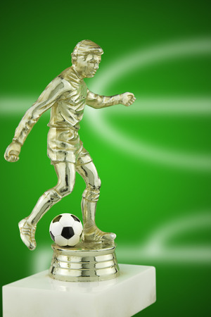 close up of a gold plastic football player trophy with a real leather footballの写真素材