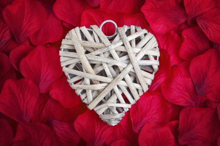 wooden love heart on red fabric rose petalsの写真素材