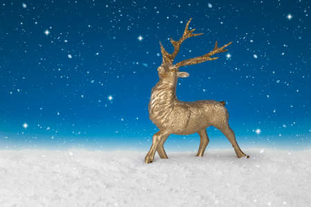 Snow falling on a gold Christmas Reindeerの写真素材