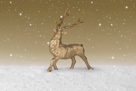 Snow falling on a gold Christmas Reindeerの写真素材