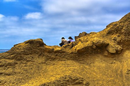 Couple sitting on cliffs overlooking the ocean.の写真素材
