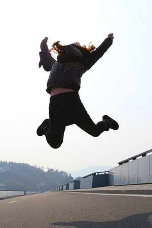 girl jumping on the roadの写真素材