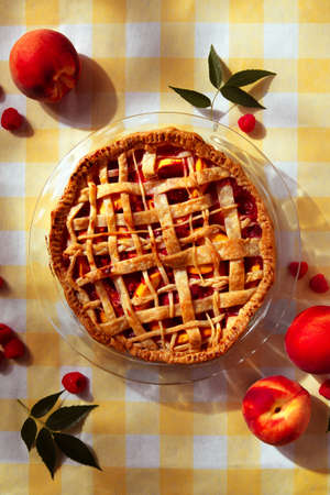 A fresh homemade raspberry and peach pie sitting outside on a summer picnic table.の写真素材